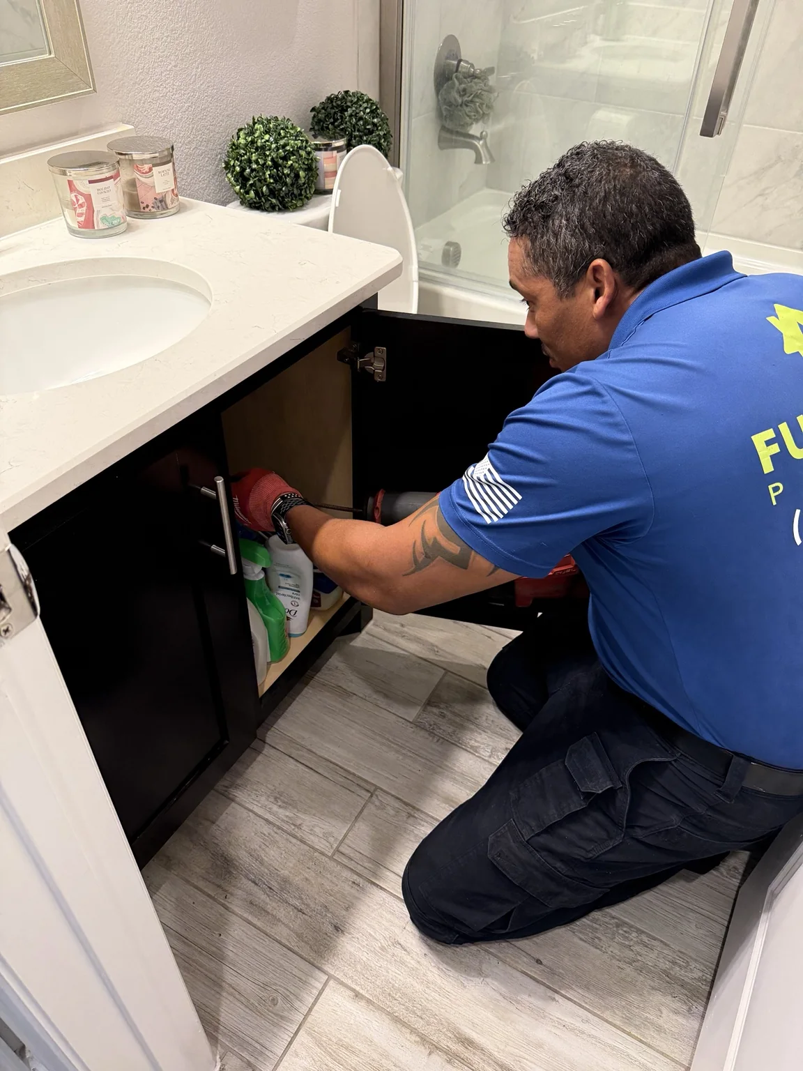 Full Force Plumbing technician working under a bathroom vanity